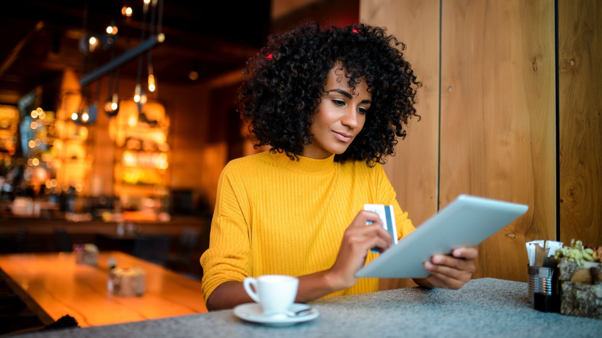 Customer making a digital purchase on her iPad in a coffee shop